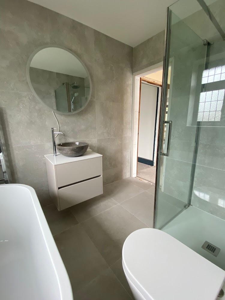 Finished bathroom with glass shower, vanity unit and round mirror
