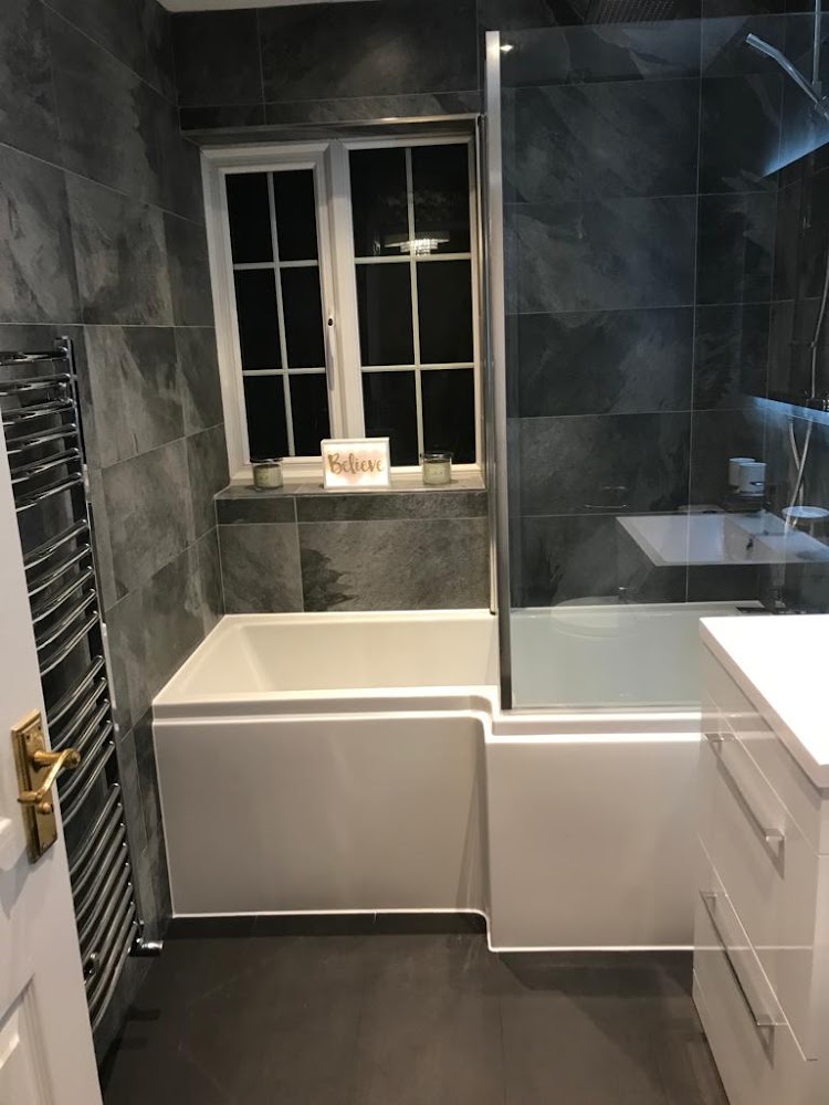 Grey tiled bathroom with shower bath and chrome towel rail