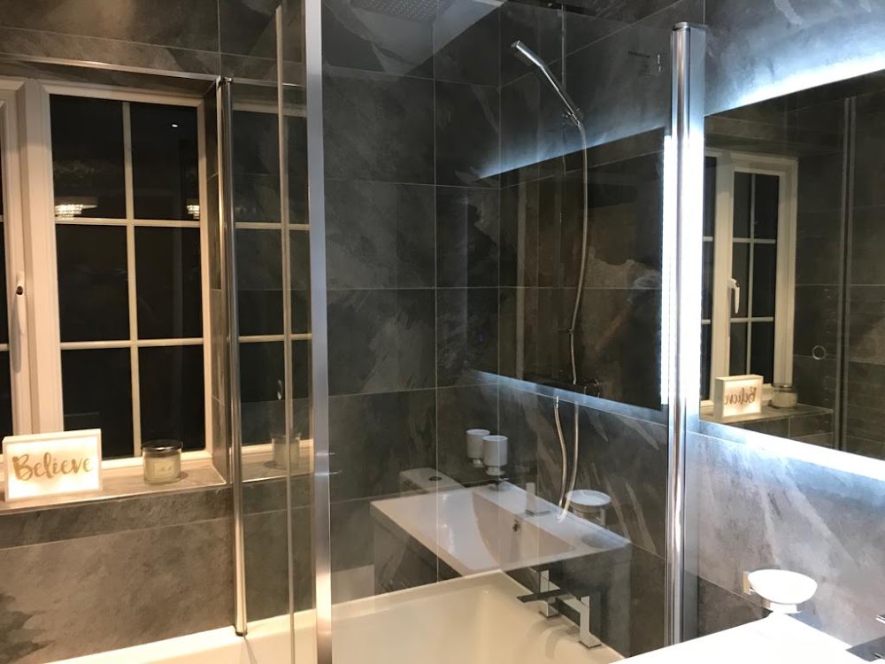 Dark tiled bathroom with glass shower screen and LED mirror