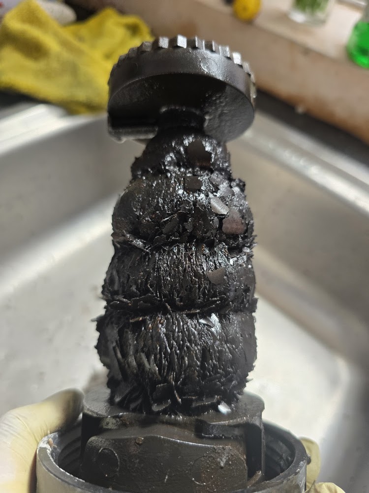 Magnetic system filter covered in black sludge removed from a heating system